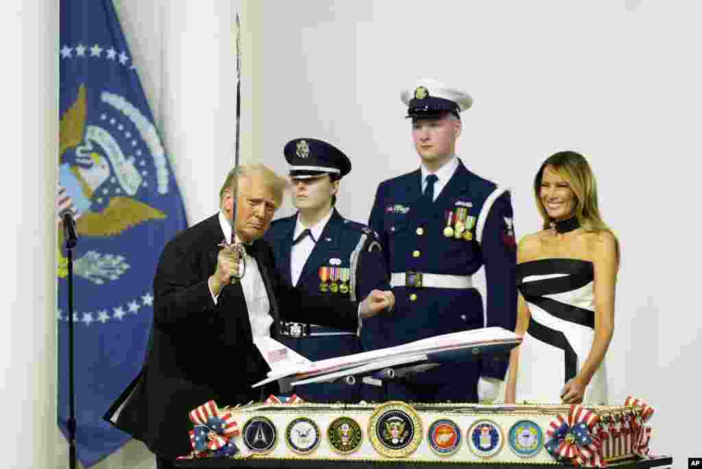 President Donald Trump, left, holds a sabre after cutting a cake as first lady Melania Trump, right, watches at the Commander in Chief Ball, Jan. 20, 2025, in Washington.