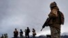 ARCHIVO - Un soldado chileno observa a un grupo de migrantes próximos a la frontera con Bolivia, cerca de la localidad de Colchane, Chile, en diciembre de 2021.