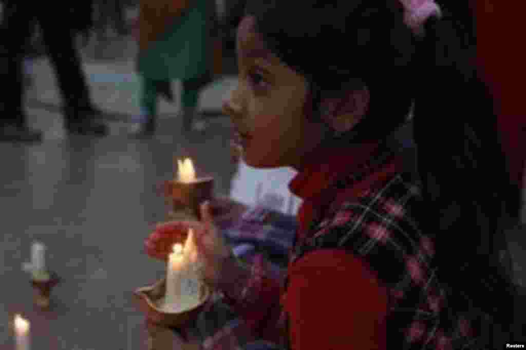 A child holds a candle while observing a global vigil for peace between India and Pakistan, in Karachi January 27, 2013.