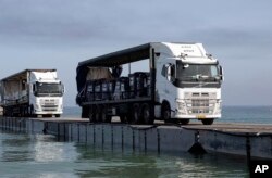 FILE - Trucks loaded with humanitarian aid from the United Arab Emirates and the U.S. Agency for International Development cross the Trident Pier before arriving on the beach on the Gaza Strip on May 17, 2024. (U.S. Army via AP)