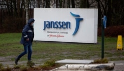 A man walks by a sign outside Johnson & Johnson subsidiary, Janssen Pharmaceutical, in Geel, Belgium, Feb. 3, 2021.
