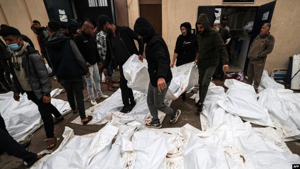 2023年12月25日，在加沙地带南部代尔巴拉赫的阿克萨医院举行集体葬礼之前，医务人员和志愿者摆放的在以色列袭击马加齐难民营时丧生人员的尸体。（法新社照片）(photo:VOA)
