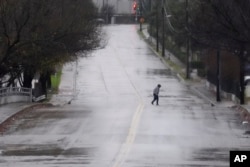 Un peatón camina por una calle empapada por la lluvia en Dallas, el jueves 26 de diciembre de 2024. (Foto AP/LM Otero)