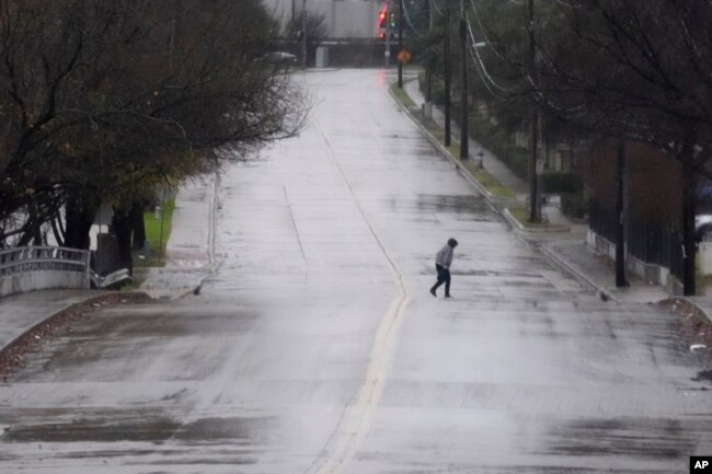 Un peatón camina por una calle empapada por la lluvia en Dallas, el jueves 26 de diciembre de 2024. (Foto AP/LM Otero)