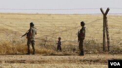 FILE - Turkish soldiers stand guard as a Syrian refugee boy waits behind border fences to cross into Turkey on the Turkish-Syrian border, near the southeastern town of Akcakale in Sanliurfa province, Turkey, June 5, 2015. A London-based Syrian monitoring group has accused Turkish border guards of having killed dozens of Syrian refugees in 2016 alone.