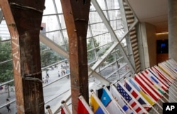 FILE - International flags hang adjacent to the top of two tridents salvaged from the World Trade Center buildings on display at the National September 11 Memorial and Museum in New York, July 11, 2017. International visits to the museum are up from last year.