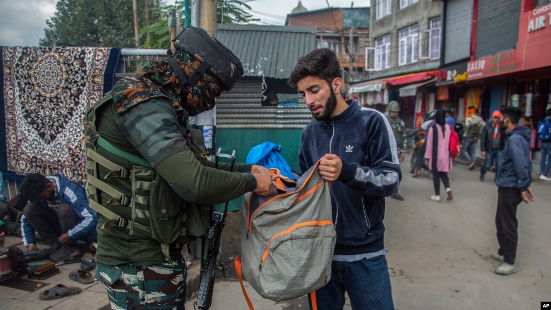 Tentara India tampak mengecek isi tas dari seorang pemuda Kashmir yang berjalan melewati area sibuk di pasar di Srinagar, wilayah Kashmir yang dikontrol oleh India, pada 11 Oktober 2021. (Foto: AP/Mukhtar Khan)