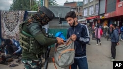 Tentara India tampak mengecek isi tas dari seorang pemuda Kashmir yang berjalan melewati area sibuk di pasar di Srinagar, wilayah Kashmir yang dikontrol oleh India, pada 11 Oktober 2021. (Foto: AP/Mukhtar Khan)