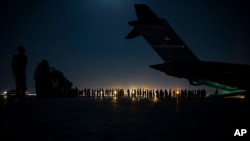 In this image provided by the US Air Force, aircrew prepare to load qualified evacuees aboard a C-17 Globemaster III aircraft in support of the Afghanistan evacuation at Hamid Karzai International Airport, Kabul, Afghanistan, Aug. 21, 2021.