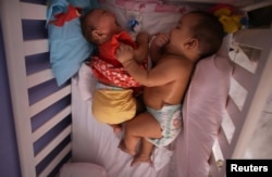 Five-month-old twins, Laura (L) and Lucas lie in their bed at their house in Santos, Sao Paulo state, Brazi, April 20, 2016.