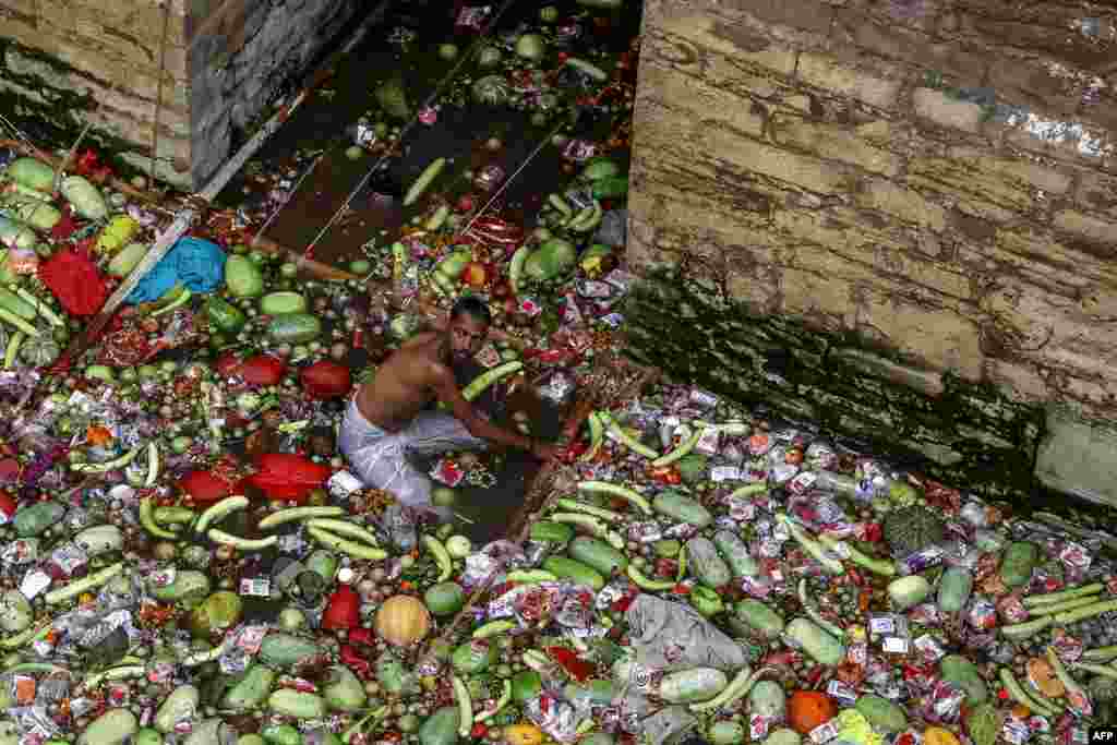 Seorang relawan memisahkan buah-buahan dan sayuran yang dipersembahkan oleh para penganut agama Hindu setelah mereka berendam di sumur suci Lolark Kund selama festival Lolark Shasthi, di Varanasi, India. (AFP)&nbsp;