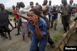 FILE - Protesters attack a policewoman in Bujumbura, Burundi, May 12, 2015, in a rally sparked by opposition to the president's decision to run for a third term.