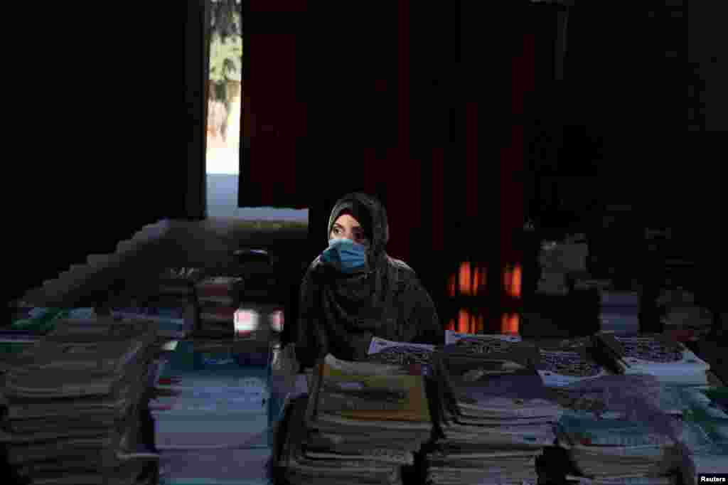 A Palestinian teacher waits to give books to students at a school as part of preparations by the Ministry of Education to reopen schools amid the COVID-19 outbreak, in the northern Gaza Strip.