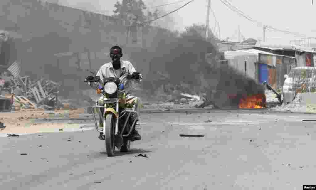 Muendesha pikipiki akipita katika eneo lililotokea mlipuko wa bomu karibu na mlango wa kuingia uwanja wa ndege wa mji mkuu wa Somalia Mogadishu, Feb. 13, 2014. 