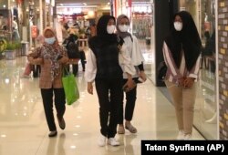 Sejumlah perempuan mengenakan masker sebagai pencegahan penyebaran virus corona berjalan di sebuah pusat perbelanjaan di Tangerang, Senin, 1 Maret 2021. (Foto: AP/Tatan Syuflana)
