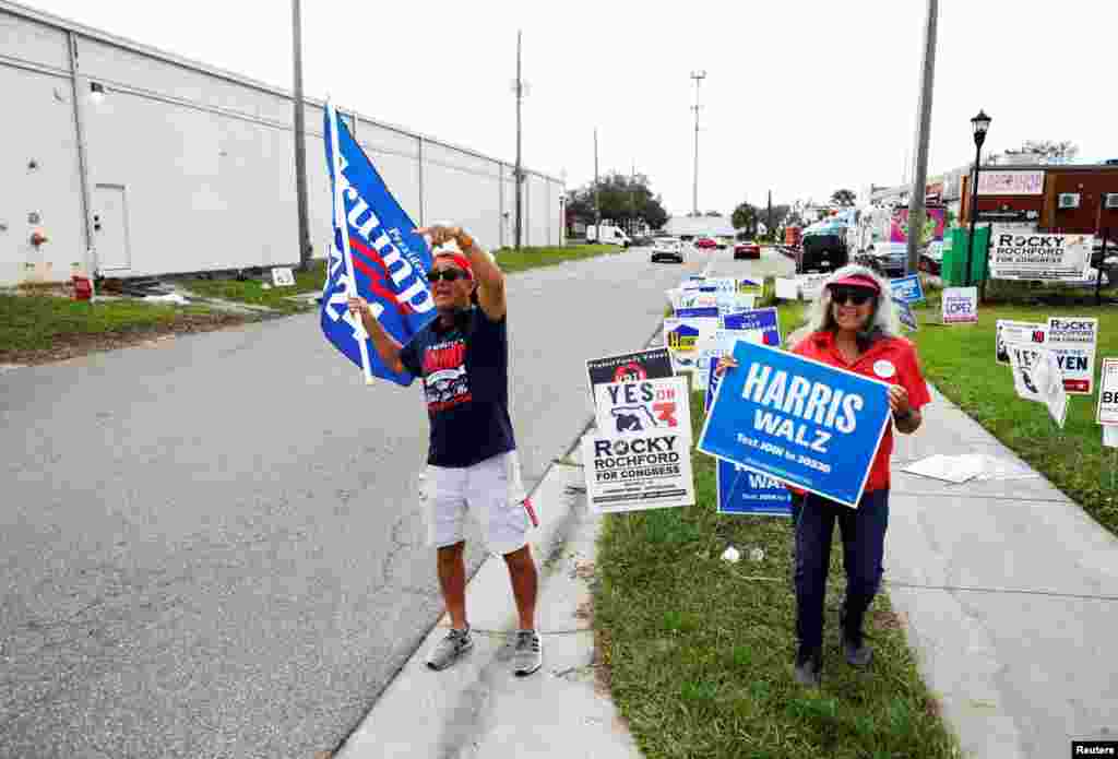 Robert Browning (L) and Terri Bieberbach wave campaign sings outside of a polling precinct on Election Day at the Town &#39;N Country Regional Public Library in Tampa, Florida.