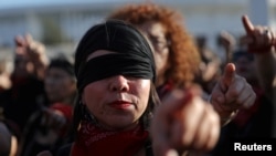 Activistas por los derechos de las mujeres con los ojos vendados participan en una protesta contra la violencia a las mujeres y contra el gobierno de Chile en Santiago.