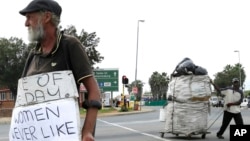 Un homme fait la manche (g) tandis qu'un autre collecte des matériaux recyclables, à une intersection de rue à Johannesburg, en Afrique du Sud, le 16 mars 2016.