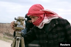 FILE - A Jaish Al-Islam (army of Islam) brigade fighter prepares to launch rockets towards forces loyal to Syria's president Bashar Al-Assad located beside Damascus International airport, from the eastern Damascus suburb of Ghouta, Feb. 24, 2015.