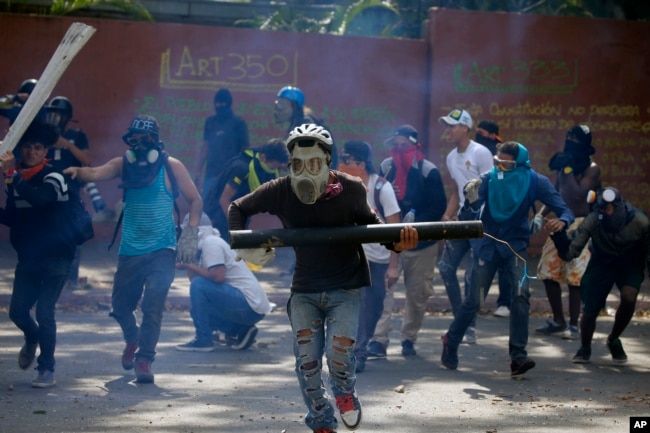 Anti-government protesters, one carrying a homemade mortar, take cover as security forces fire tear gas to disperse demonstrators in Caracas, Venezuela, May 1, 2019.