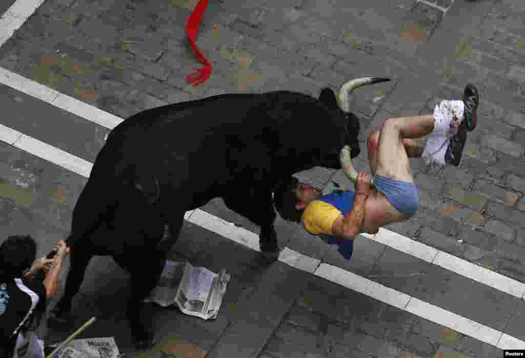 A runner is gored by an El Pilar fighting bull on Estafeta street during the sixth running of the bulls of the San Fermin festival in Pamplona, Spain, July 12, 2013.