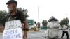 Un homme fait la manche (g) tandis qu'un autre collecte des matériaux recyclables, à une intersection de rue à Johannesburg, en Afrique du Sud, le 16 mars 2016.