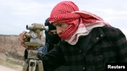 FILE - A Jaish Al-Islam (army of Islam) brigade fighter prepares to launch rockets towards forces loyal to Syria's president Bashar Al-Assad located beside Damascus International airport, from the eastern Damascus suburb of Ghouta, Feb. 24, 2015. 