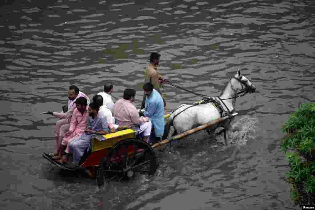 لاہور کی ایک زیر آب شاہراہ سے تانگے پر سوار افراد اپنے گھروں کو لوٹ رہے ہیں جبکہ تقریباً نصف تانگا زیر آب ہے۔ شہر میں بارش کے پانی نے سیلابی صورتحال اختیار کی ہوئی ہے