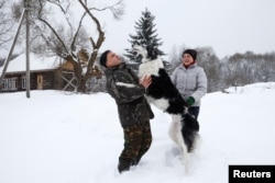Dmitry Shamovich and his wife, Anastasia Kuzmenkova, play with the dog Amur at their homestead Zaimka Leshego in the village of Sosnovy Bor, Belarus, Feb. 7, 2018.