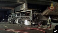 Un pompier essaie d’éteindre le feu sur la carcasse brûlée d'un autobus qui s'est écrasé et pris feu près de Vérone, Italie, 21 janvier 2017. 