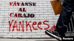 A man walks past graffiti which reads "Yankees, go to hell" in Caracas, March 10, 2015.
