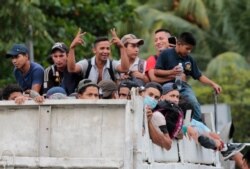 Migrants get a free ride from a trucker toward the Guatemalan border after leaving San Pedro Sula, Honduras, Oct. 1, 2020.