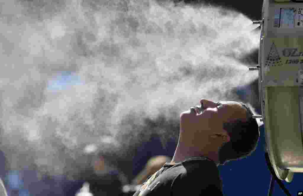 A spectator cools down at a water spraying fan at the Australian Open tennis championships in Melbourne, Australia.
