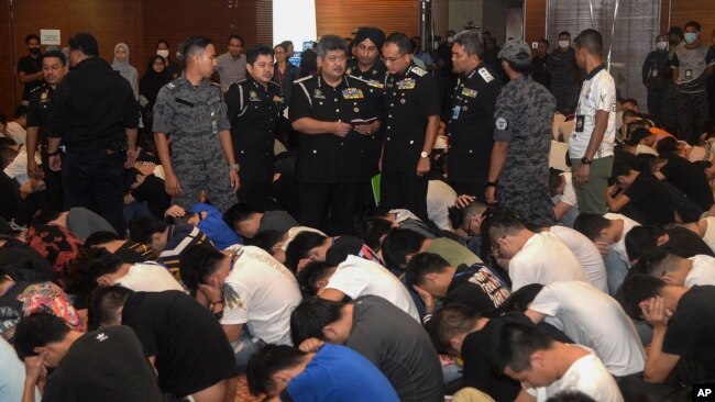马来西亚移民官2019年11月21日在布城检查被关押的中国人的旅行证件。马来西亚移民官星期四说，他们破获了一个中国网络欺诈集团，逮捕了680名中国嫌犯。