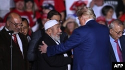 Former U.S. President and Republican presidential nominee Donald Trump greets local Muslim leaders who endorsed him onstage during a campaign rally at the Suburban Collection Showplace in Novi, Michigan, on Oct. 26, 2024.