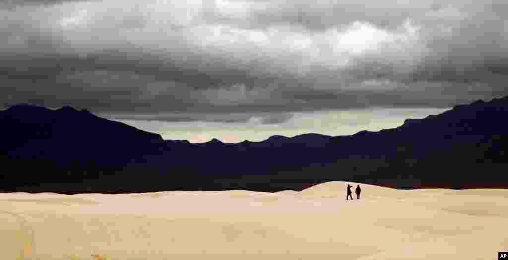 Visitors walk across dunes at White Sands National Monument as a rain storm passes, Feb. 10, 2019, near Alamogordo, New Mexico.