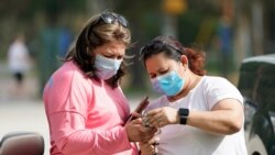 Women wear masks as they check a mobile phone on July 1, 2020, in Houston.