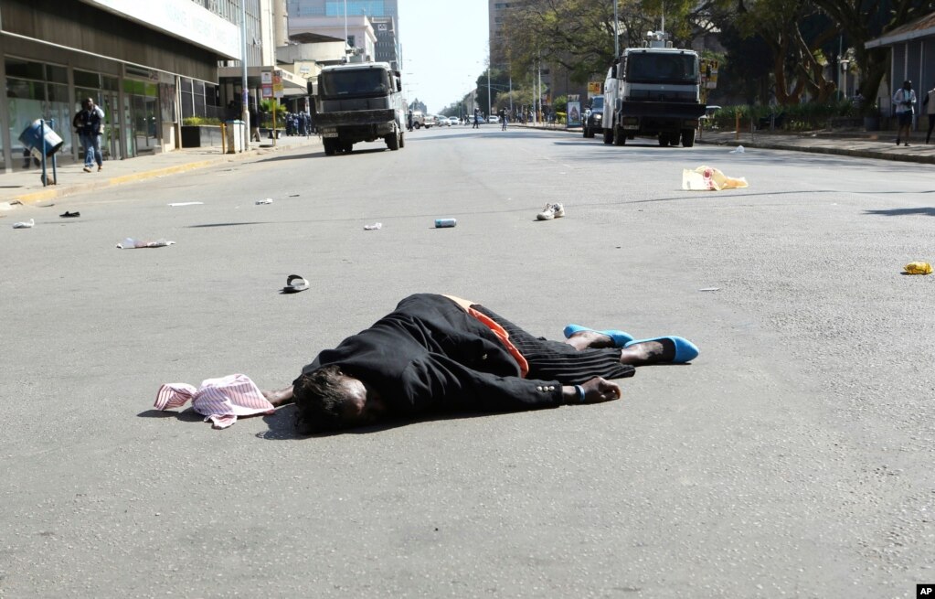 A woman lies in the road after Zimbabwean police wounded her during protests in Harare.