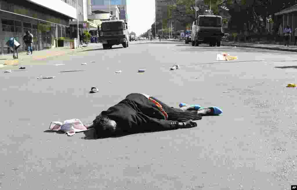 A woman lies in the road after Zimbabwean police wounded her during protests in Harare.