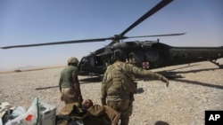 Dua tentara AS mengangkut rekannya yang terluka dalam pertempuran di Afghanistan (foto: dok).