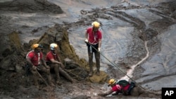 FILE - Rescue workers take a rest from their search for victims at the town of Bento Rodrigues, after a dam burst in Minas Gerais state, Brazil, Nov. 8, 2015.