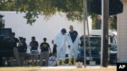 Members of the FBI walk behind the First Baptist Church of Sutherland Springs after a fatal shooting, Nov. 5, 2017, in Sutherland Springs, Texas.