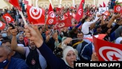 Des Tunisiens brandissent le drapeau national lors d'une manifestation contre le président Saied le long de l'avenue Habib Bourguiba dans la capitale Tunis, le 10 octobre 2021.