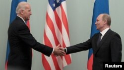 FILE - Russian Prime Minister Vladimir Putin (R) shakes hands with then-U.S. Vice President Joe Biden during their meeting in Moscow March 10, 2011.