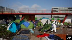 A Paris town hall worker clears a migrant makeshift camp, in Paris, May 30, 2018. 