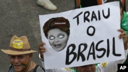 Yon fanm brezilyèn kenbe nan men li yon postè ki montre yon karikati Prezidan Dilma Rousseff avèk mo sa yo: "Li trayi Brezil" pandan yon manifestasyon kote moun yo tap mande jije e revoke prezidan an. (Foro: AP Photo/Eraldo Peres)