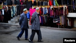 FILE - Two ethnic Uighur men walk in a clothing market in downtown Urumqi, Xinjiang province.