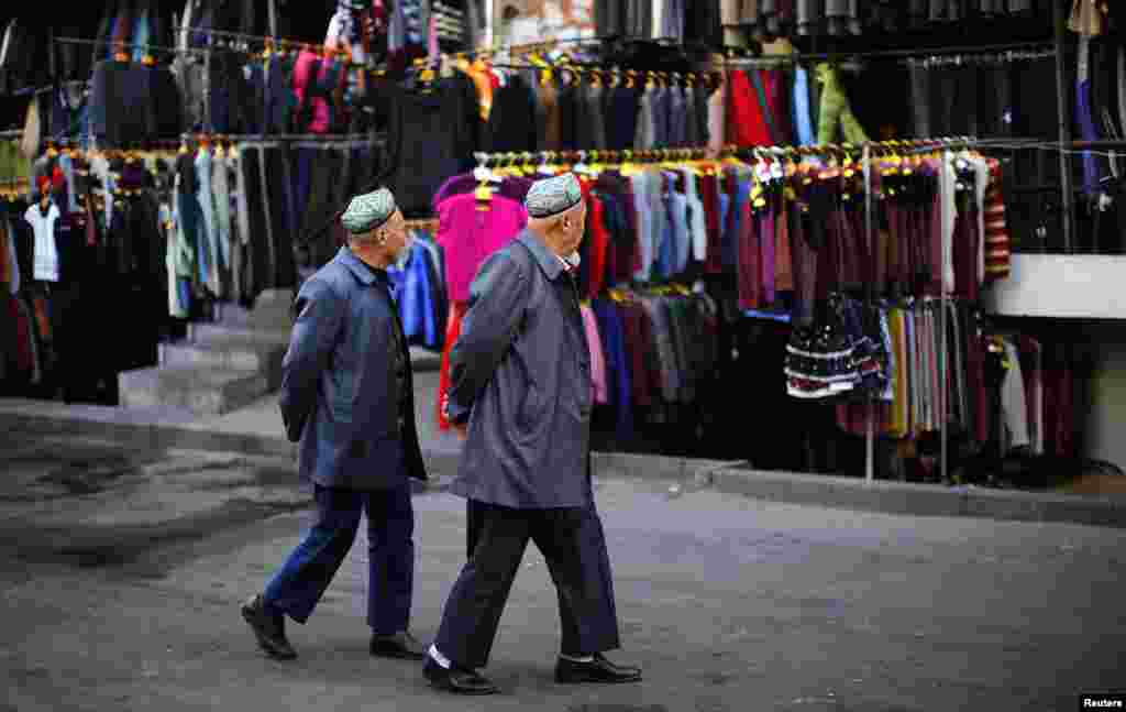 دو مرد اویغور در حال قدم زدن در بازار لباس در مرکز اورومچی، استان سین کیانگ - اول نوامبر ۲۰۱۳