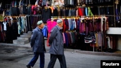 FILE - Two ethnic Uighur men walk in a clothing market in downtown Urumqi, Xinjiang province.