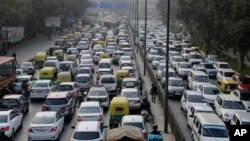 In this Jan. 16, 2016, file photo, vehicles move slowly through a traffic intersection after the end of a two-week experiment to reduce the number of cars to fight pollution in in New Delhi, India. (AP Photo/Altaf Qadri, File)